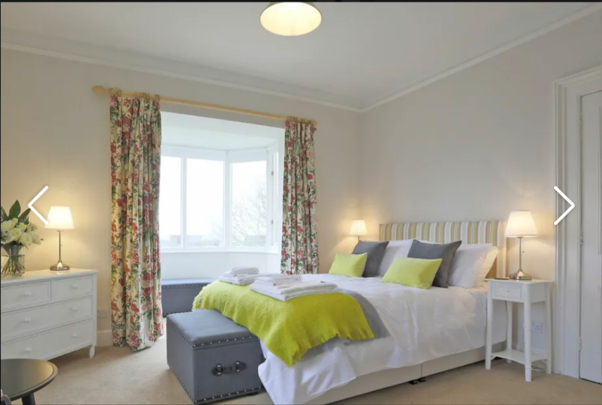 Bright, cozy bedroom with floral curtains and green accents.