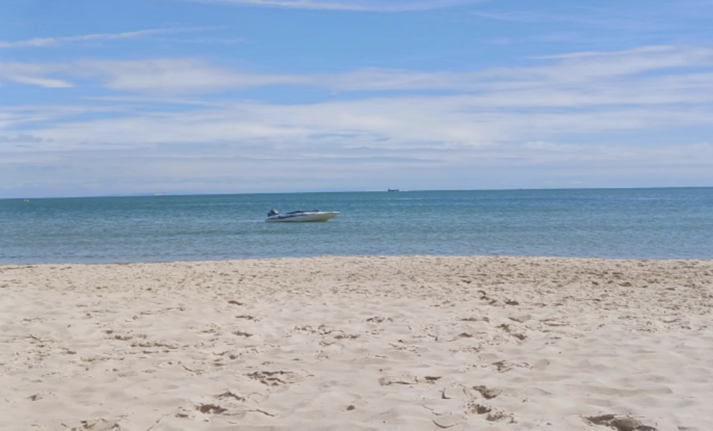 Sandy beach with boat on clear day